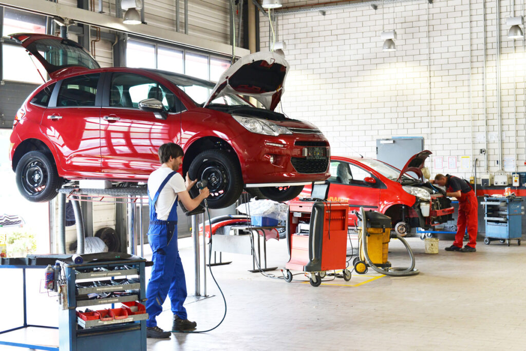 mécanicien réparant les roues d'une voiture sur un monte-charge dans un garage